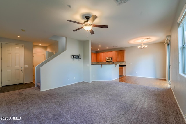 unfurnished living room featuring light carpet and ceiling fan with notable chandelier