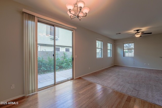 spare room with ceiling fan with notable chandelier and hardwood / wood-style floors