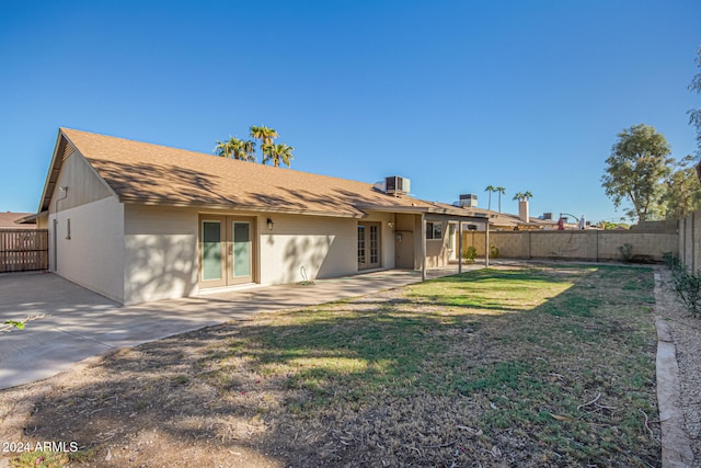 rear view of house featuring central AC, a patio area, a lawn, and french doors