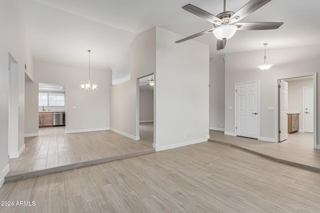 spare room featuring ceiling fan with notable chandelier, light hardwood / wood-style flooring, sink, and vaulted ceiling