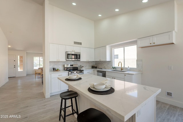 4037 E Milton Dr, Cave Creek, AZ 85331 - kitchen featuring appliances with stainless steel finishes, light wood-type flooring, light stone countertops, white cabinetry, and a towering ceiling