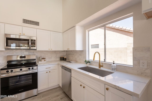 4037 E Milton Dr, Cave Creek, AZ 85331 - kitchen with appliances with stainless steel finishes, tasteful backsplash, white cabinetry, and light stone counters