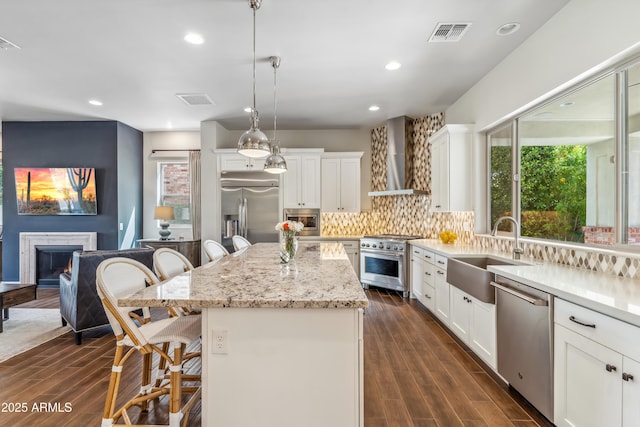 625 W Echo Ln, Phoenix, AZ 85021 - kitchen featuring a sink, built in appliances, wall chimney exhaust hood, a breakfast bar area, and visible vents