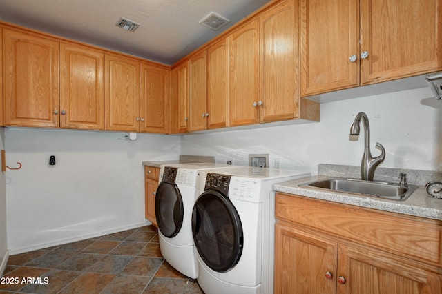 washroom with cabinets, washing machine and dryer, and sink