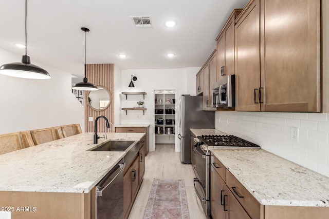 8640 W Frier Dr, Glendale, AZ 85305 - kitchen featuring stainless steel appliances, a sink, open shelves, an island with sink, and tasteful backsplash