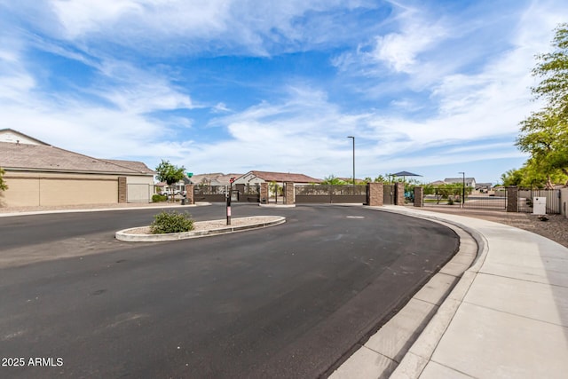 8640 W Frier Dr, Glendale, AZ 85305 - view of asphalt street with a gate, sidewalks, curbs, and street lights