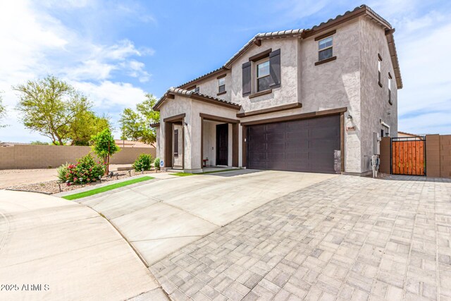 8640 W Frier Dr, Glendale, AZ 85305 - mediterranean / spanish-style home with concrete driveway, a garage, a gate, stucco siding, and a tiled roof