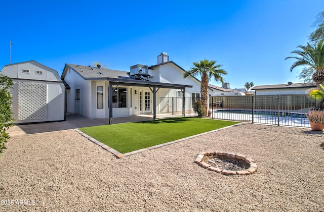 back of property featuring a patio area, central AC, fence, a fenced in pool, and a fire pit