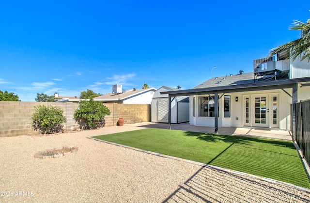 rear view of property with a yard, a patio, french doors, and a fenced backyard