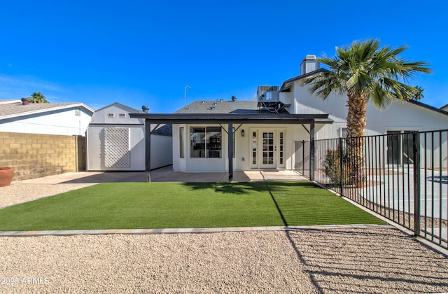rear view of house featuring a chimney, a lawn, central AC unit, a patio area, and a fenced backyard