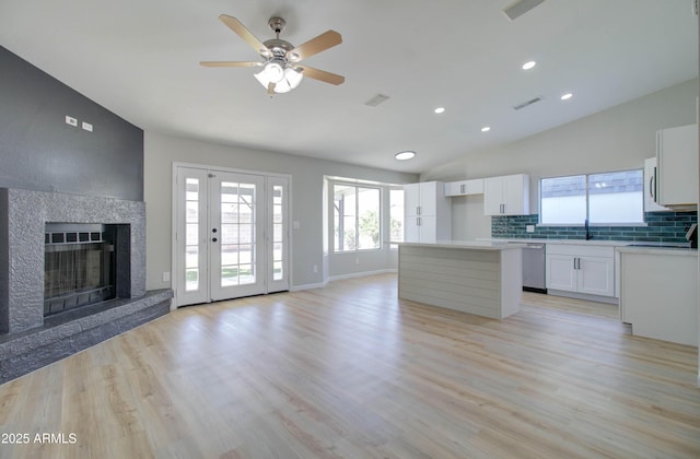 kitchen with ceiling fan, open floor plan, decorative backsplash, a kitchen island, and visible vents