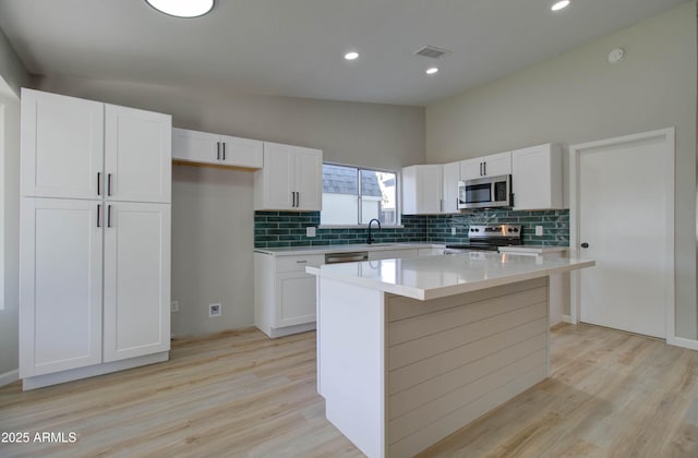 kitchen with visible vents, backsplash, vaulted ceiling, and stainless steel appliances
