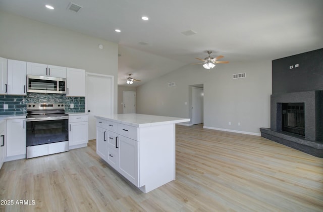kitchen with stainless steel appliances, open floor plan, visible vents, and a ceiling fan