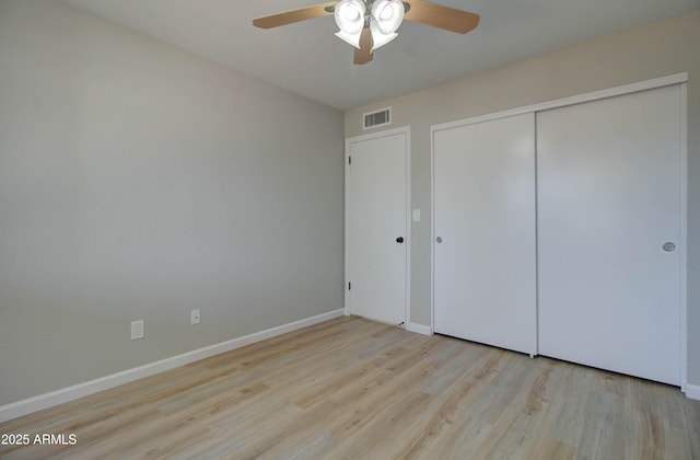 unfurnished bedroom with visible vents, a closet, wood finished floors, baseboards, and a ceiling fan