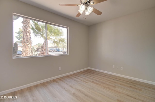 spare room with baseboards, ceiling fan, and light wood finished floors