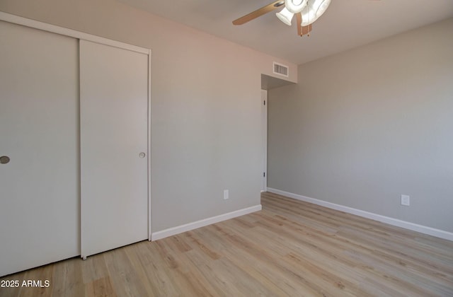 unfurnished bedroom with baseboards, visible vents, wood finished floors, and a closet