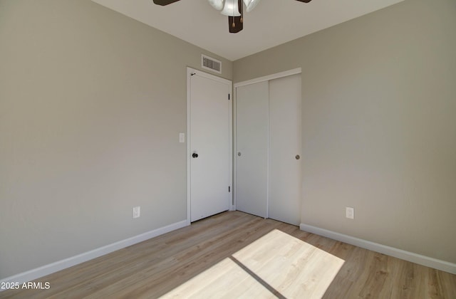 unfurnished bedroom with baseboards, wood finished floors, visible vents, and a closet