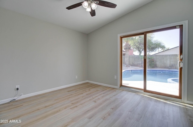 empty room with ceiling fan, vaulted ceiling, baseboards, and light wood-style floors