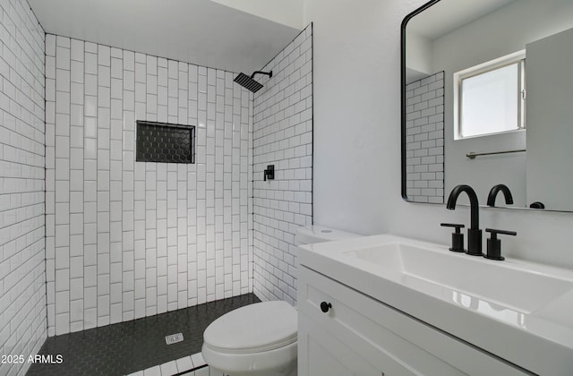 full bath featuring vanity, toilet, and tiled shower