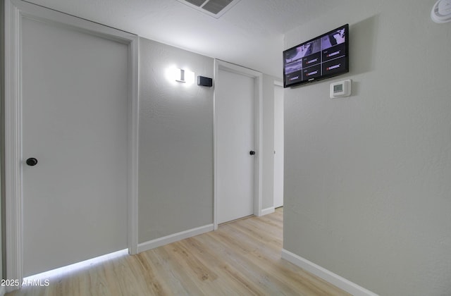 corridor with baseboards, wood finished floors, and visible vents