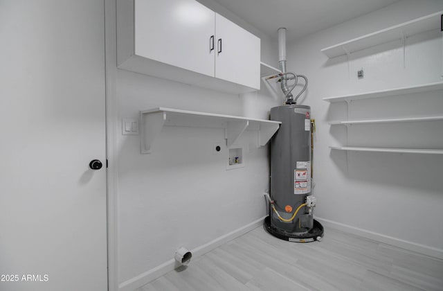 washroom featuring hookup for an electric dryer, cabinet space, wood finished floors, baseboards, and water heater