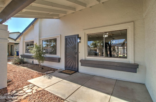 entrance to property featuring a patio and stucco siding