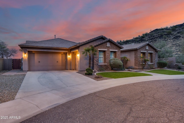 ranch-style home with a tile roof, stone siding, fence, concrete driveway, and an attached garage