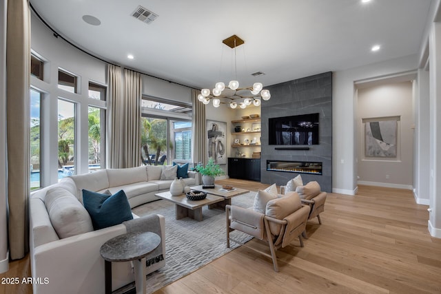 living area with a large fireplace, baseboards, visible vents, and light wood-type flooring