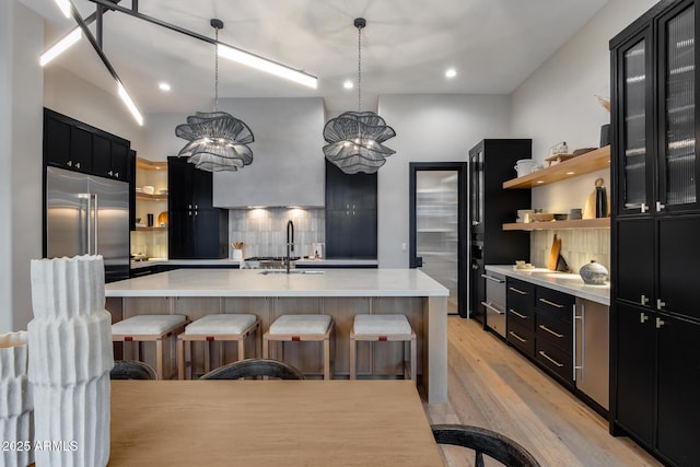 kitchen featuring open shelves, light countertops, dark cabinets, and built in refrigerator