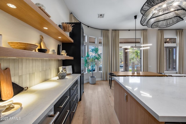 kitchen with light wood finished floors, visible vents, pendant lighting, and open shelves