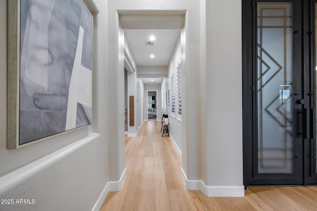 corridor featuring visible vents, light wood-type flooring, and baseboards