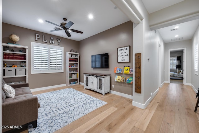 living room with light wood-type flooring, visible vents, baseboards, and a ceiling fan