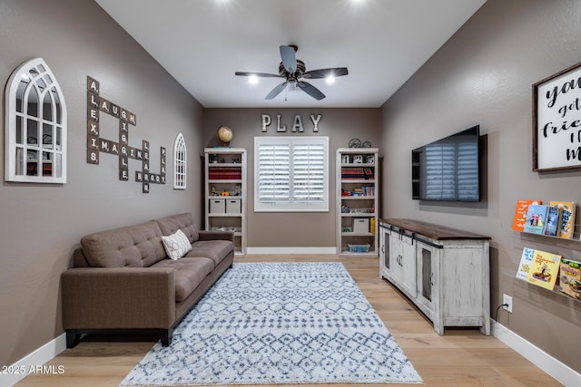 living area with baseboards, light wood finished floors, and ceiling fan