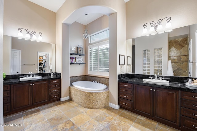 full bathroom featuring a bath, two vanities, and a sink