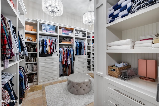 walk in closet featuring stone finish flooring and a chandelier