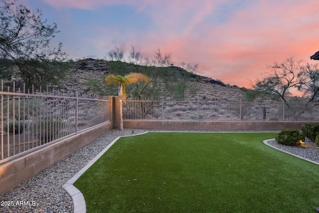 yard at dusk featuring a fenced backyard