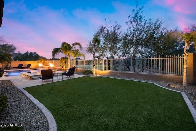 yard at dusk with a patio area, a fenced backyard, and an outdoor fire pit