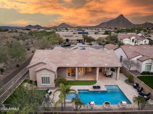 rear view of property featuring a patio, a fenced backyard, stucco siding, a tile roof, and a mountain view