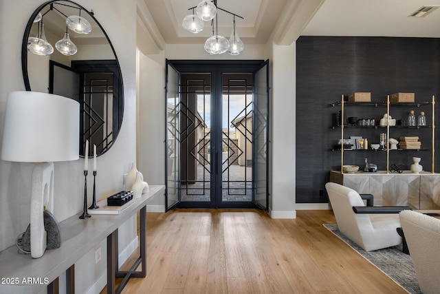 entrance foyer featuring visible vents, wood finished floors, baseboards, french doors, and a raised ceiling