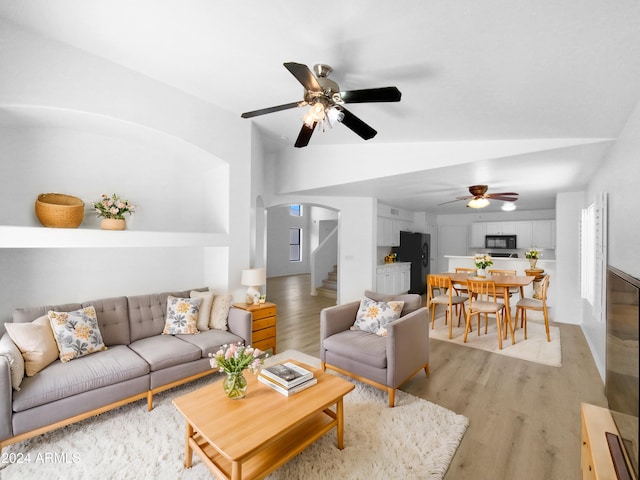 living room featuring ceiling fan, light wood-type flooring, and vaulted ceiling