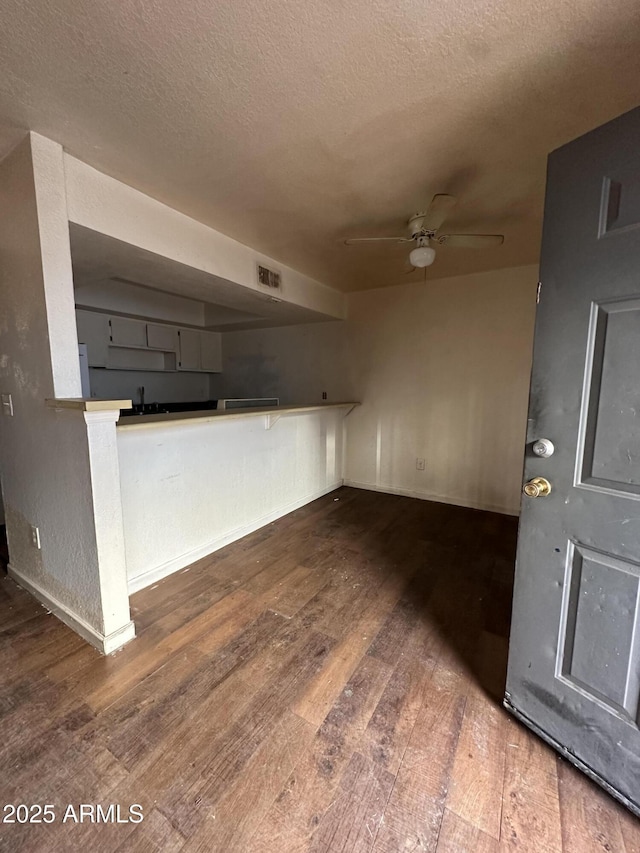 unfurnished living room with ceiling fan, dark hardwood / wood-style floors, and a textured ceiling