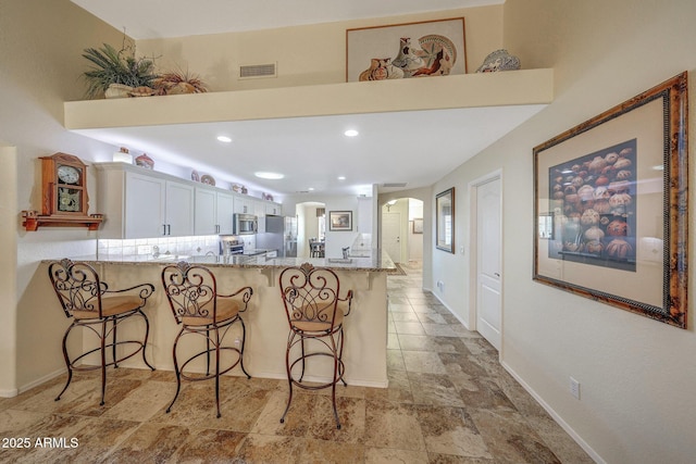 11047 W Irma Ln, Peoria, AZ 85373 - kitchen featuring stainless steel appliances, a breakfast bar, arched walkways, visible vents, and a peninsula