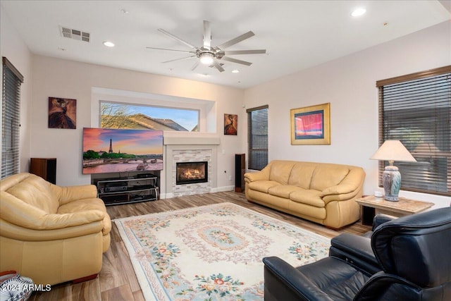 living room with recessed lighting, visible vents, a ceiling fan, a stone fireplace, and wood finished floors