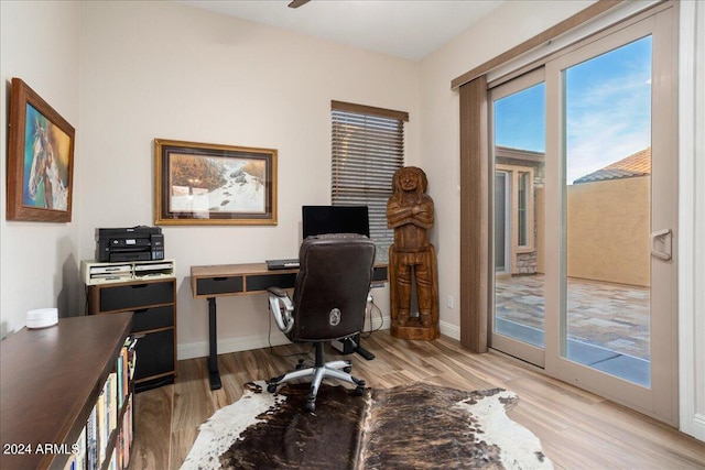 home office featuring light wood finished floors, baseboards, and a ceiling fan