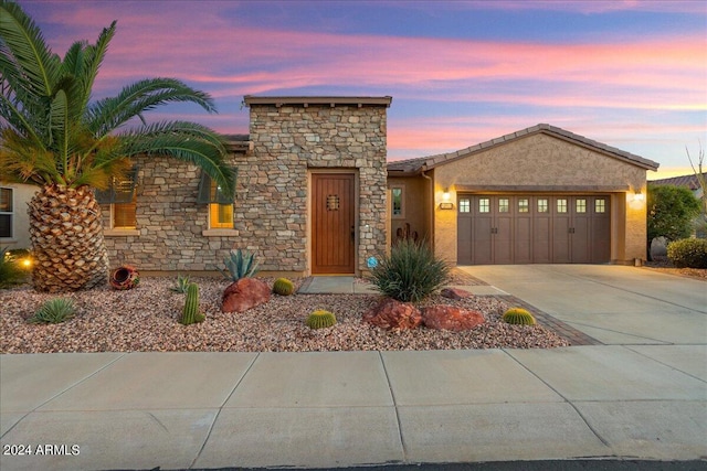 view of front of home with an attached garage, stone siding, concrete driveway, and stucco siding