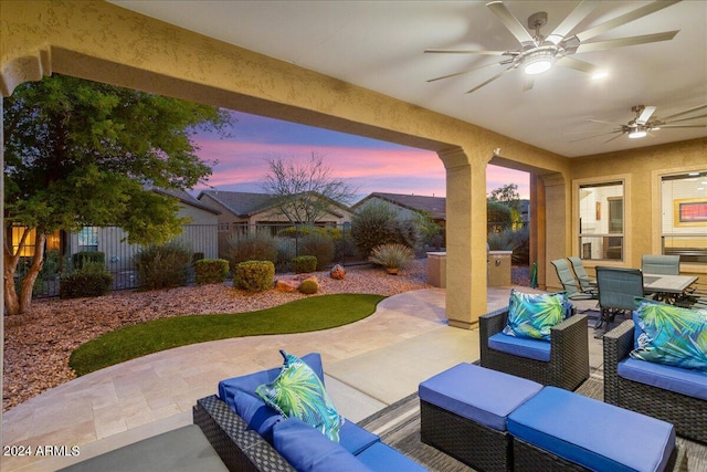 patio terrace at dusk featuring ceiling fan, fence, outdoor lounge area, and outdoor dining space