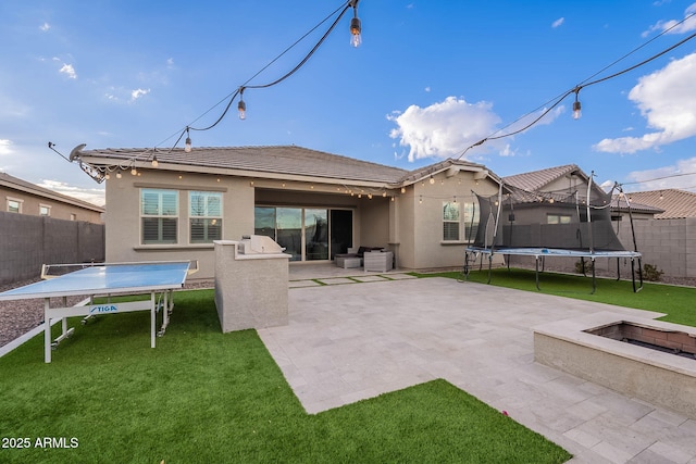 rear view of property with a patio area, a yard, and a trampoline