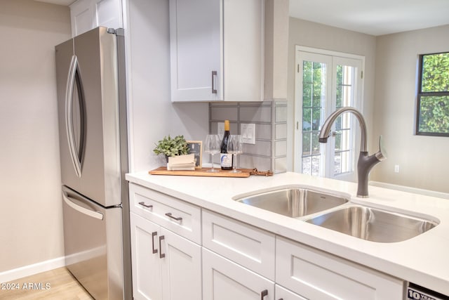 kitchen with light hardwood / wood-style floors, sink, stainless steel fridge, and white cabinets