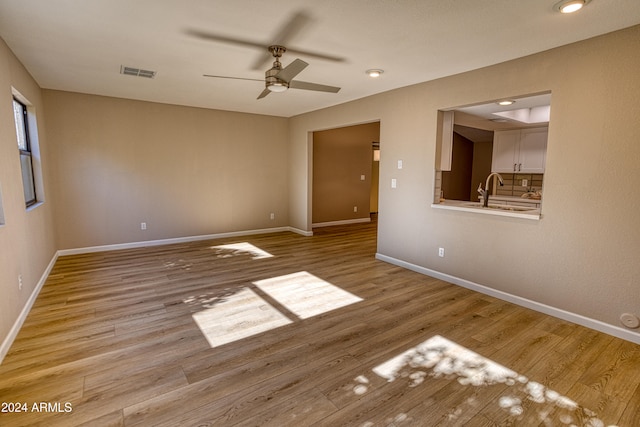 unfurnished room with ceiling fan, sink, and light hardwood / wood-style floors