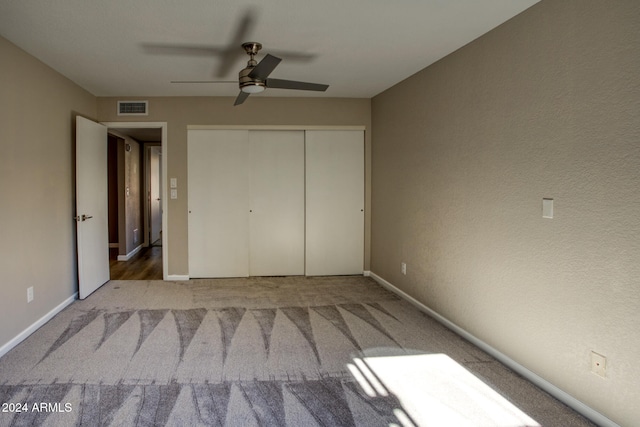 unfurnished bedroom featuring a closet, light colored carpet, and ceiling fan